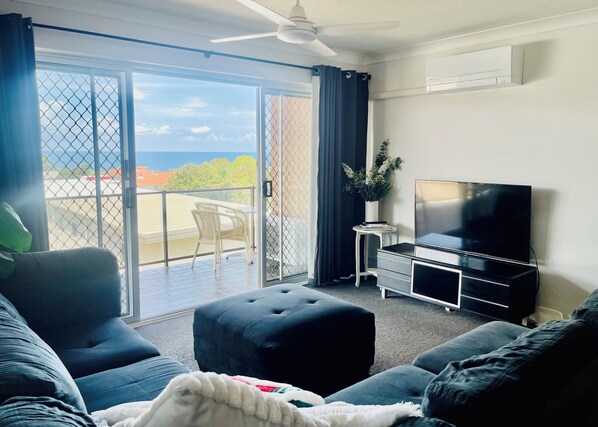 Relax in this stylish living room with a balcony offering breathtaking views of the sea and surrounding buildings.