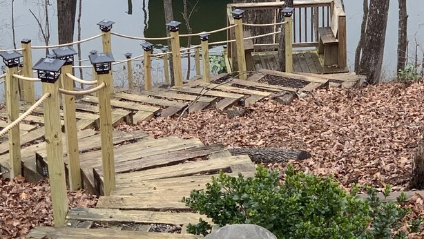 Un muelle de madera con una barrera de cuerda que lleva a una pequeña plataforma de madera.