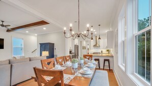 A modern dining area with a wooden table set for six, surrounded by wooden chairs. - Luxurious Living in Old Town Bluffton! Sleeps 6! Prime Location! (Bluffton)