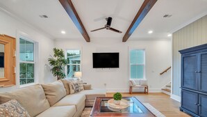 A spacious living room with a large sofa, a coffee table, and a ceiling fan. - Luxurious Living in Old Town Bluffton! Sleeps 6! Prime Location! (Bluffton)