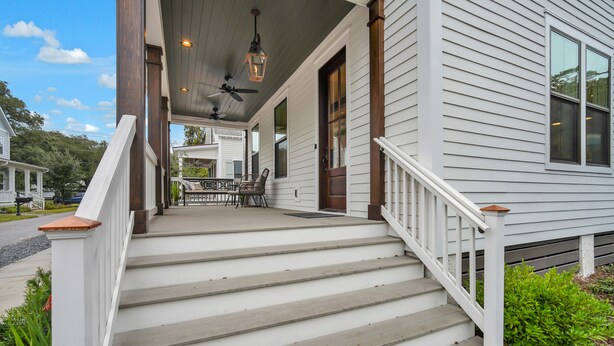 A house with a porch, wooden steps, a dining table with chairs, and a ceiling fan. - Luxurious Living in Old Town Bluffton! Sleeps 6! Prime Location! (Bluffton)