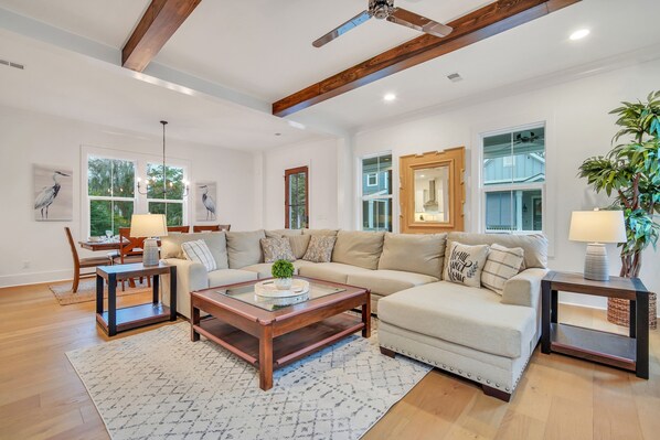 A spacious living room with a large sectional sofa, a wooden coffee table, and a chandelier.