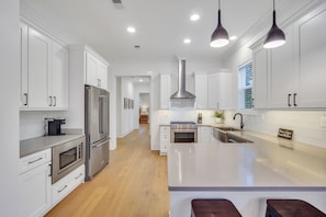 A modern kitchen with white cabinetry, stainless steel appliances, and a central island.