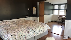 Un dormitorio con cama, un felpudo blanco y mullido, una silla de madera y una puerta que da a otra habitación.
