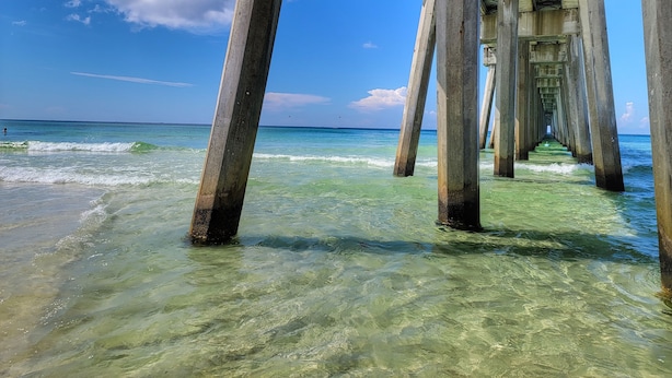 Eine Pier, die sich in klares türkisblaues Wasser erstreckt, mit blauem Himmel darüber.