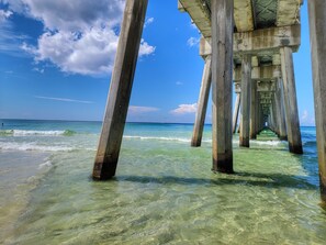A pier extending into clear turquoise water with a clear sky above.
