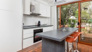 A modern kitchen with white cabinets, a central island, and a sliding glass door leading to an outdoor patio.