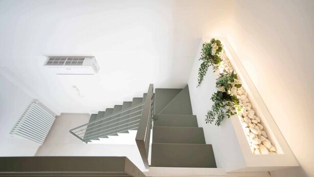A modern staircase with a metal railing, a white wall, and a decorative plant arrangement. - WePuglia - Dimore Stefania - Suite Piazzetta (Polignano a Mare)