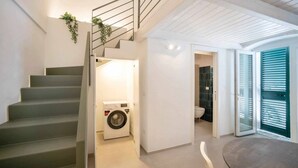 A modern interior with a staircase, a washing machine, and a bathroom. - WePuglia - Dimore Stefania - Suite Piazzetta (Polignano a Mare)