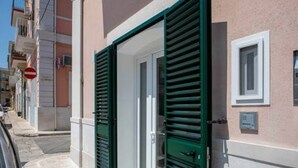 A narrow street with buildings, a closed green shutter door, and a red 'no entry' sign. - WePuglia - Dimore Stefania - Suite Piazzetta (Polignano a Mare)