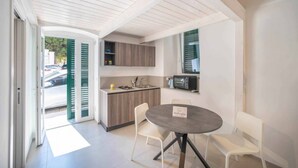 A compact kitchen with a dining area, a built-in microwave, and a small island with a sink. - WePuglia - Dimore Stefania - Suite Piazzetta (Polignano a Mare)