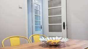 A dining area with a wooden table, yellow chairs, and a decorative bowl. - North Star Flats @dom Luís I Bridge (Vila Nova de Gaia)