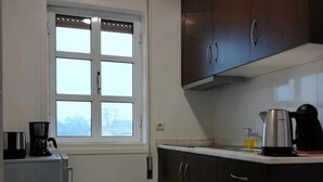 A kitchen with a window, a refrigerator, dark cabinets, and a coffee maker. - North Star Flats @dom Luís I Bridge (Vila Nova de Gaia)