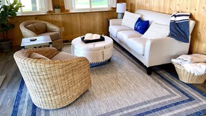 A cozy living room with wicker furniture, a white sofa, and a patterned rug. - Grey Wolf Family Style Cottage on Wolf Lake Waterfront (Grass Lake)