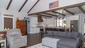 Un salón amplio con un sofá seccional gris, un sillón gris y una alfombra estampada.