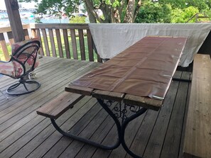 Une terrasse en bois avec une table de pique-nique recouverte d’une nappe marron.