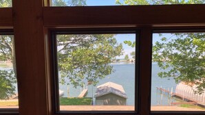 Ein Zimmer mit Blick auf einen See durch ein Fenster, ein Monopoly-Spiel und ein weißer Stuhl.