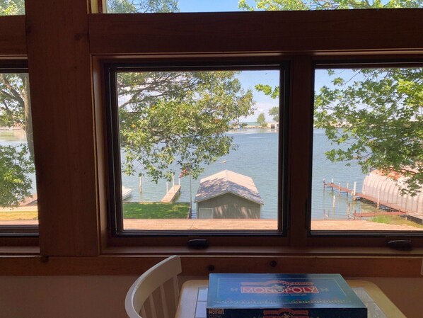 A room with a view of a lake through a window, a Monopoly board game, and a white chair.