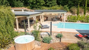 Un giardino sul retro con idromassaggio, piscina e patio coperto con mobili da esterno.