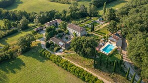 Vista aerea di una struttura con diversi edifici, una piscina e vegetazione circostante.