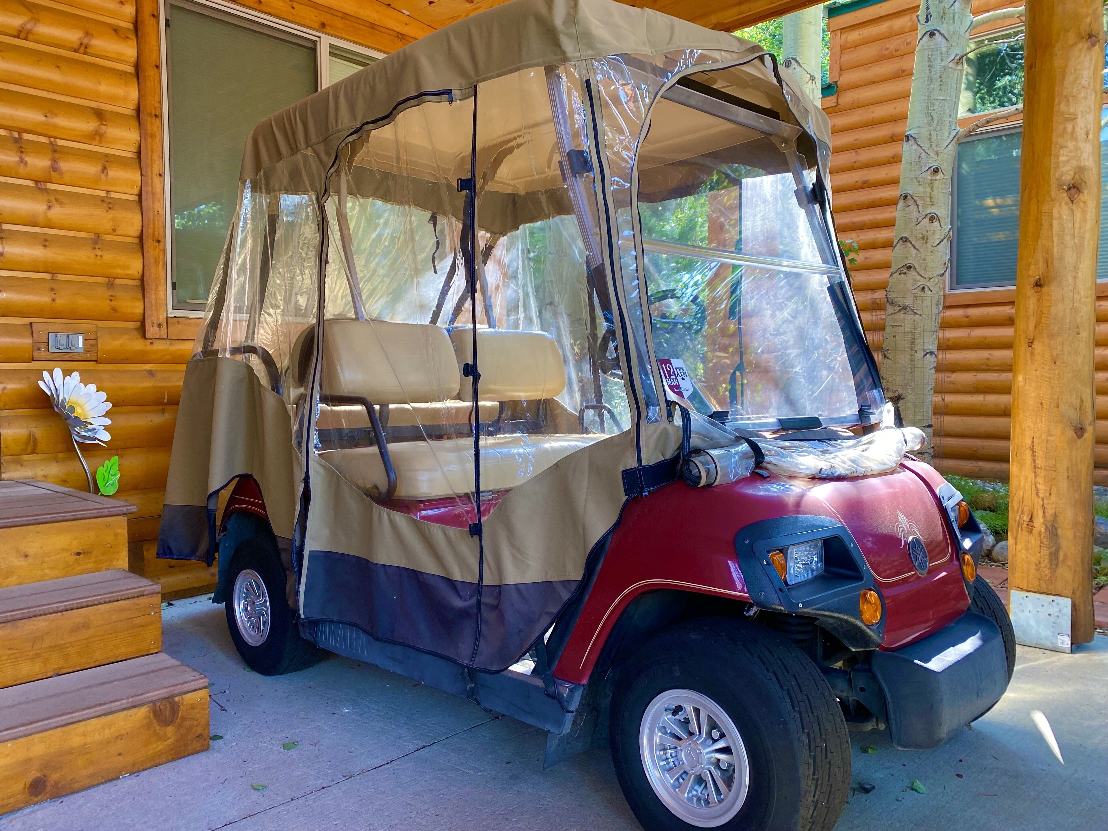 Un vehículo cubierto estacionado frente a una cabaña de madera.