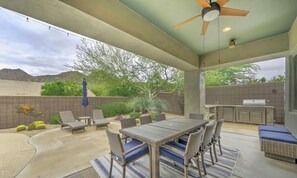 An outdoor patio with a dining table and chairs, a ceiling fan, and a barbecue grill.
