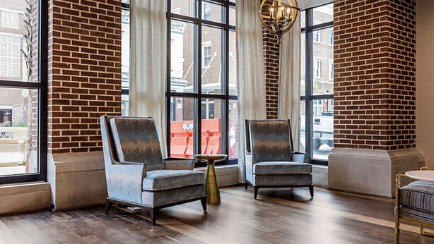 A modern interior with two armchairs, a small round table, and a sofa. Large windows with curtains are visible. - Charleston 1BR Deluxe Prime King Street property (Charleston)