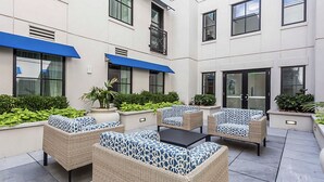 A courtyard with wicker furniture, potted plants, and a blue awning. - Charleston 1BR Deluxe Prime King Street property (Charleston)