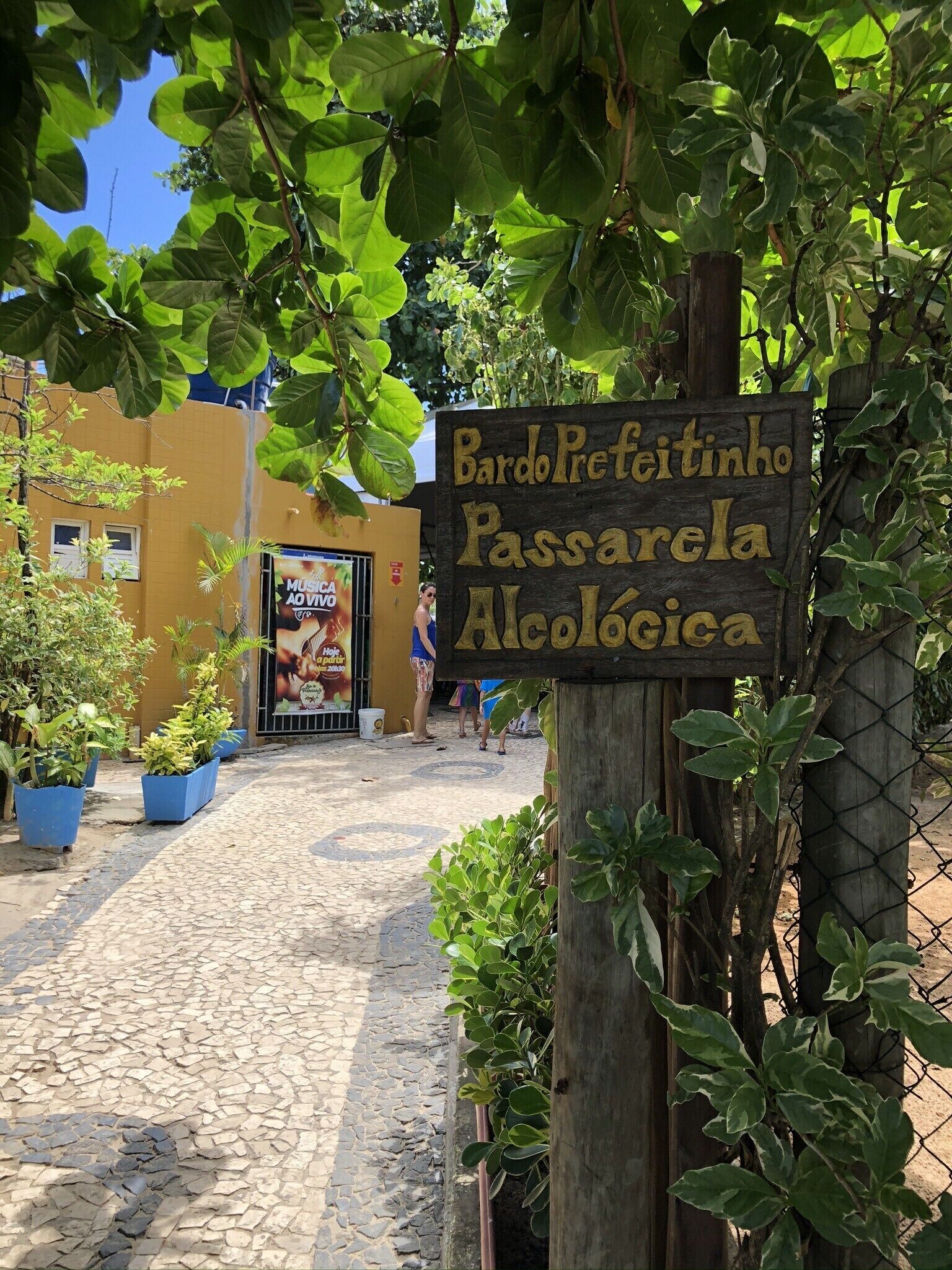 A cobblestone street with a wooden sign for Bardo Pretinho Passarela Aleológica.