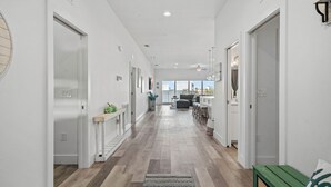 A modern hallway with a wooden floor, white walls, and a view to the outside.