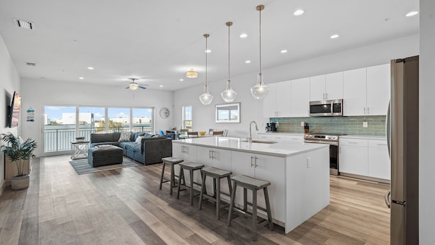 A spacious kitchen with a central island, bar stools, and a dining area with a sofa.