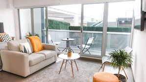 A modern living room with a sofa, a small round table, and a potted plant. - Cozy Studio Perfect to Home Office or Relax (San José)
