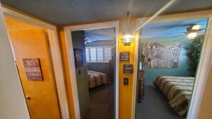 A hotel room with a bed, a nightstand, and a wall-mounted lamp. - Bakersfield Safari Retreat (Bakersfield)