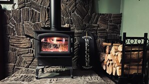 A wood-burning stove with a welcome sign, set against a stone wall.