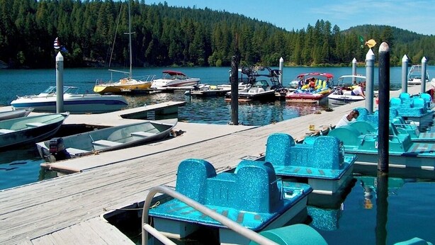 A dock with several boats and paddle boats.