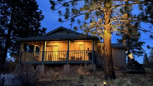 A wooden cabin with a porch, surrounded by trees and rocks.