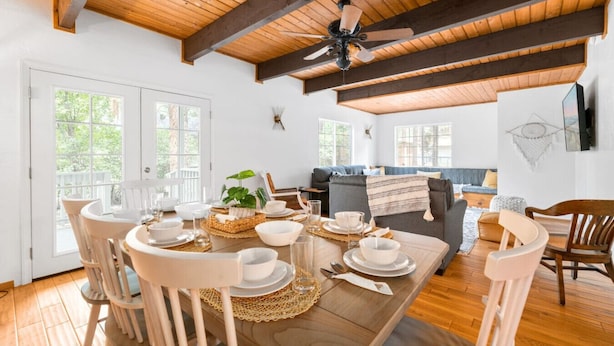 Un coin repas avec une table en bois dressée pour quatre personnes, entourée de chaises blanches.