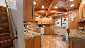 Une cuisine avec des meubles en bois, des plans de travail en granit et un sol carrelé.