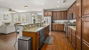 Una cocina amplia con armarios de madera, encimeras de granito y electrodomésticos de acero inoxidable.