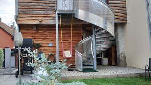 A log cabin with a spiral staircase, a hanging chair, and a garden area with plants. - House (Wintzenheim)