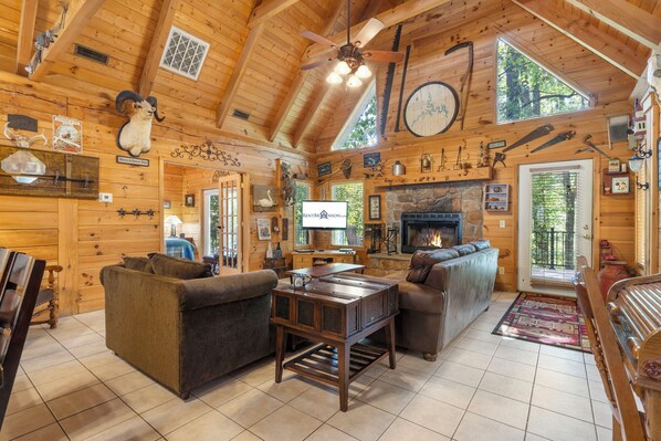 A cozy log cabin interior with a fireplace, wooden furniture, and various hunting trophies on the walls. - Rustic Log Cabin Near Thunder Ridge w Private Hot Tub & Free Attraction Tickets_Community Amenities! (Ridgedale)