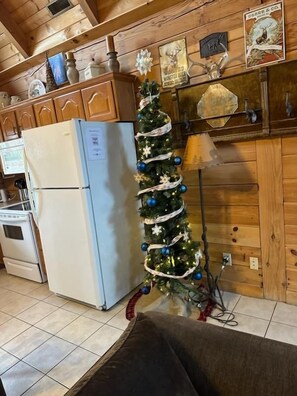 A kitchen with wooden cabinets, a refrigerator, a Christmas tree, and a stove. - Rustic Log Cabin Near Thunder Ridge w Private Hot Tub & Free Attraction Tickets_Community Amenities! (Ridgedale)