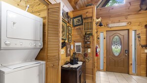 A kitchen with a white appliance, wooden walls, and a door labeled "HOME". - Rustic Log Cabin Near Thunder Ridge w Private Hot Tub & Free Attraction Tickets_Community Amenities! (Ridgedale)