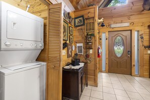 A kitchen with a white appliance, wooden walls, and a door labeled "HOME". - Rustic Log Cabin Near Thunder Ridge w Private Hot Tub & Free Attraction Tickets_Community Amenities! (Ridgedale)