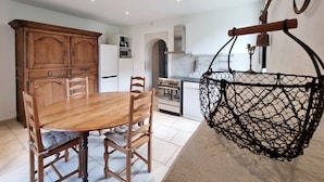 A dining area with a wooden table and chairs, a white refrigerator, and a hanging chair.