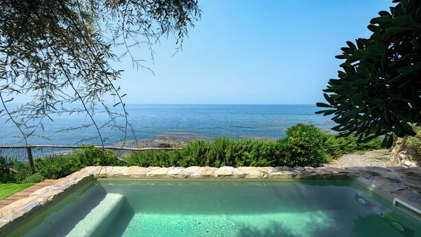 A rectangular swimming pool with clear water, surrounded by a stone border, and overlooking a rocky coastline. - Casa Frontemare con Scesa al Mare Privata (Castiglioncello (LI))