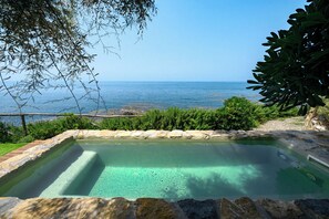 A rectangular swimming pool with clear water, surrounded by a stone border, and overlooking a rocky coastline. - Casa Frontemare con Scesa al Mare Privata (Castiglioncello (LI))