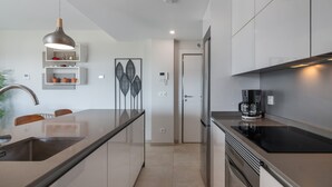 A modern kitchen with a large island, stainless steel appliances, and a pendant light. - Los Flamencos Penthouse by Ĥ - Haraganes Beach HLHF4501P43 (Isla Canela)
