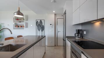 Een moderne keuken met een groot eiland, roestvrijstalen apparatuur en een hanglamp.