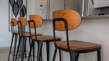 Cozinha moderna com bancada branca, pia de aço inoxidável e uma peça de arte decorativa na parede.